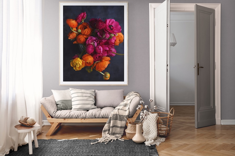 May include: A framed photograph of a bouquet of orange and pink ranunculus flowers against a dark blue background.