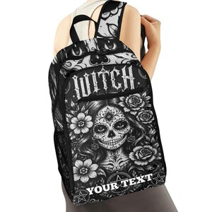 Op de afbeelding: Een zwart-witte rugzak met een grafische print van een gezicht in sugar skull-stijl omringd door bloemen. Het woord WITCH staat bovenaan in een verweerd lettertype en de tekst YOUR TEXT staat onderaan in een wit lettertype.