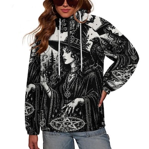 May include: A black and white long-sleeve quarter-zip pullover featuring an intricate graphic print of a witch wearing a pointed hat, a raven perched on a shoulder, and multiple pentagram symbols integrated into the detailed forest background.