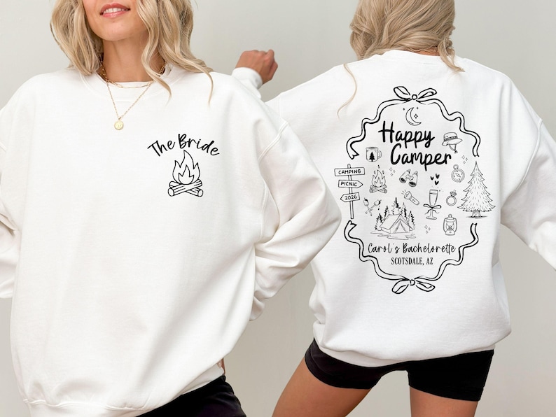 K&ouml;nnte beinhalten: Wei&szlig;es Sweatshirt mit schwarzen Grafiken. Auf der Vorderseite steht "The Bride" &uuml;ber einer Lagerfeuer-Illustration. Auf der R&uuml;ckseite steht "Happy Camper" mit Camping-Symbolen und "Carol's Bachelorette Scottsdale, AZ".