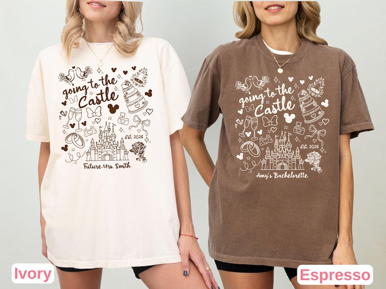 May include: Ivory and espresso-colored t-shirts with a whimsical design. The shirts feature the text "going to the Castle" with a castle illustration, Mickey Mouse ears, and other wedding-themed graphics. The ivory shirt says "Future Mrs. Smith" and the espresso shirt says "Amy's Bachelorette".