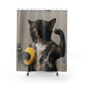 May include: A shower curtain featuring a wet tortoiseshell cat with its eyes closed, covered in white soap suds, holding a yellow sponge in one paw and flexing the other arm while standing under a stream of water in a tiled shower stall.