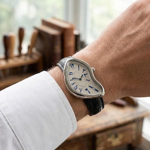 May include: A silver wristwatch with a distinctive, melting design. The white face displays blue Arabic numerals and hands. The watch is fitted with a black leather strap.