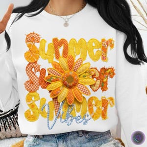 Op de afbeelding: Witte sweatshirt met de woorden "Summer Vibes" in geel, oranje en blauw. Het woord "Summer" wordt drie keer herhaald, met een grote zonnebloem in het midden. De letters zijn gemaakt van stof met verschillende patronen.