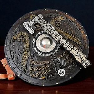 Puede incluir: Vista cenital detallada de un escudo y un hacha vikingos. El escudo es marrón oscuro con intrincados diseños dorados y plateados, incluyendo un jefe central de metal. El hacha, con cabeza plateada y mango detallado, descansa sobre el escudo.