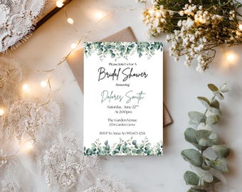 Puede incluir: Una tarjeta de invitación blanca para una despedida de soltera, con hojas de eucalipto verdes y el texto "Please Join Us For A Bridal Shower Honoring Dolores Smith". La tarjeta incluye la fecha, hora y detalles del lugar.