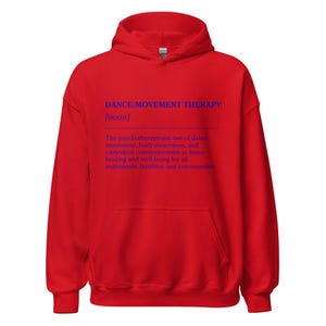 May include: A red hooded sweatshirt with a front pocket. The text "DANCE/MOVEMENT THERAPY [noun]" is printed in blue, along with a definition. The definition describes the psychotherapeutic use of dance, movement, and body awareness.