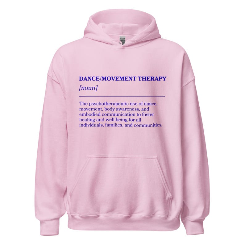 May include: A light pink hoodie with a drawstring hood and a kangaroo pocket. The front of the hoodie features the text "DANCE/MOVEMENT THERAPY [noun]" in purple, along with a definition of the term.
