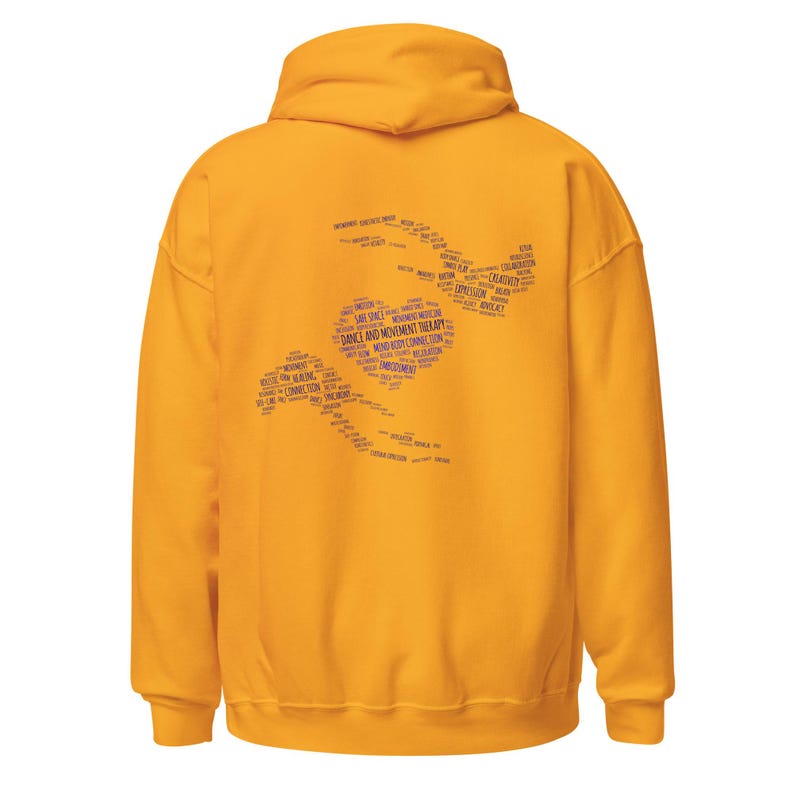 May include: Mustard yellow hoodie with a hood. The back of the hoodie features a purple design composed of words related to dance and movement therapy. The words are arranged in a stylized shape.