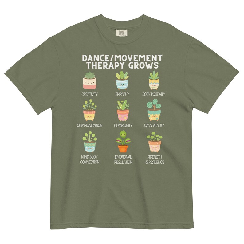 May include: Olive green t-shirt with the text "DANCE/MOVEMENT THERAPY GROWS" above illustrations of potted plants. Each plant represents a positive concept like creativity, empathy, and joy & vitality.