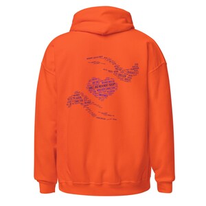 May include: An orange hoodie with a hood and long sleeves. The back of the hoodie features a blue graphic of a heart and two stylized figures, with the words "DANCE AND MOVEMENT THERAPY" and other related terms.