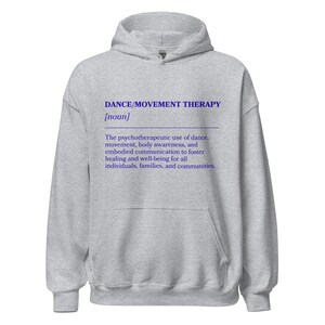 May include: A light gray hoodie with the text "DANCE/MOVEMENT THERAPY [noun]" in blue. The text below describes the psychotherapeutic use of dance, movement, body awareness, and embodied communication to foster healing and well-being.