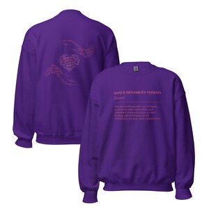 May include: A purple sweatshirt with the text "DANCE/MOVEMENT THERAPY" in pink. The definition of dance movement therapy is printed below the title. The back of the sweatshirt has a pink heart design with words.