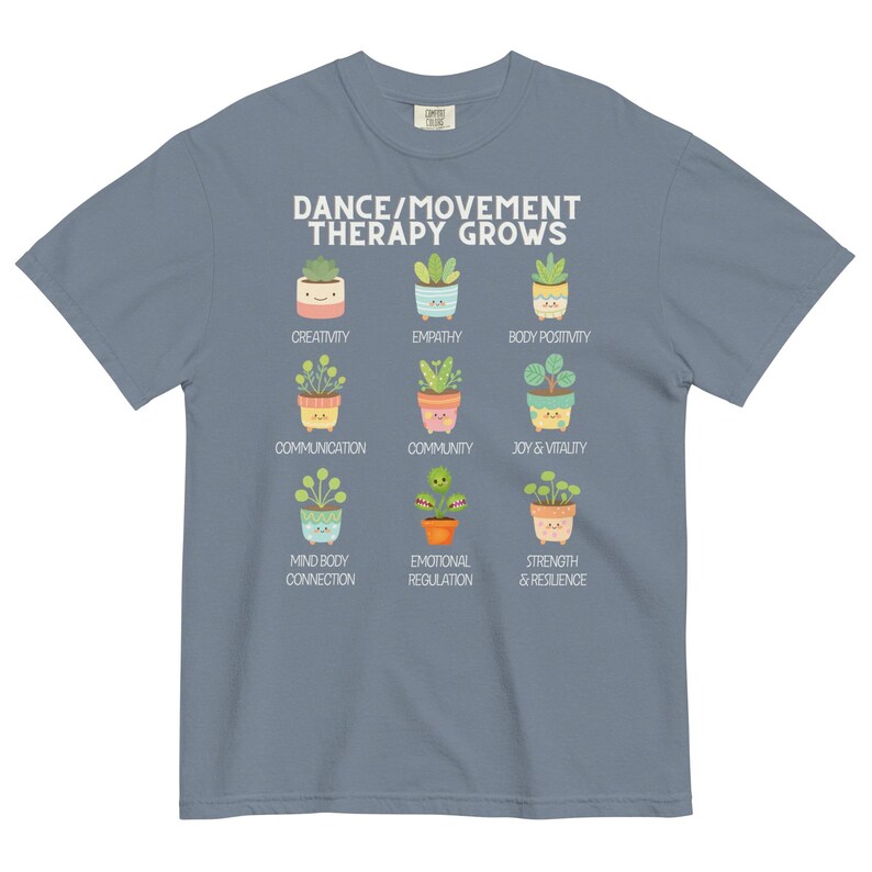 May include: A blue t-shirt with the text "DANCE/MOVEMENT THERAPY GROWS" and illustrations of potted plants representing concepts like creativity, empathy, and joy. The shirt is a comfortable, casual wear item.