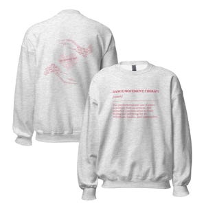 May include: A light gray sweatshirt with the text "DANCE/MOVEMENT THERAPY [noun]" in pink on the front. The back of the sweatshirt has a pink design made of text. The sweatshirt is a crew neck style.