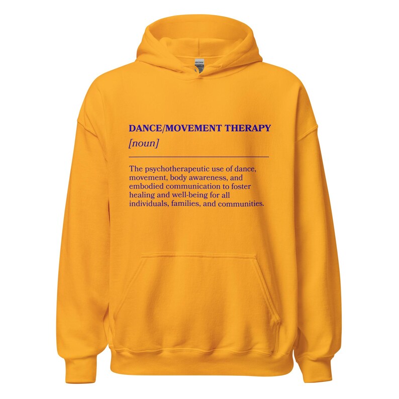 May include: Mustard yellow hoodie with a front pocket and a hood. The text "DANCE/MOVEMENT THERAPY [noun]" is printed in purple, along with a definition of the term. The hoodie is made of a soft material.