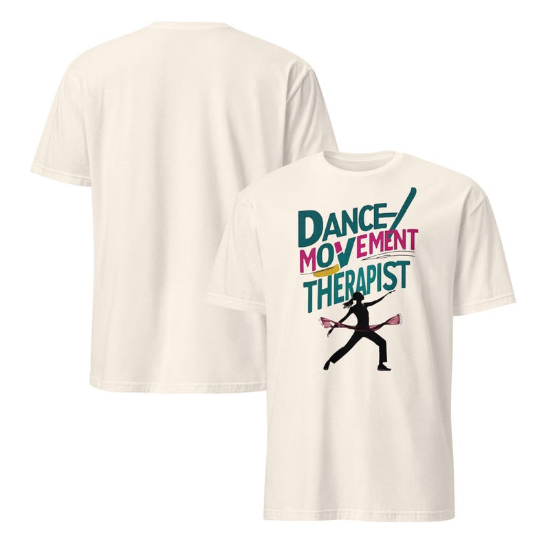 May include: Off-white t-shirt featuring the text "DANCE MOVEMENT THERAPIST" in teal, pink, and yellow. A black silhouette of a dancer is in the center. The back of the shirt is plain off-white.