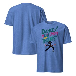 May include: Two blue t-shirts. The front shirt has the words "DANCE MOVEMENT THERAPIST" in teal, pink, and yellow. A black silhouette of a person dancing with two props is below the text. The back of the shirt is plain.