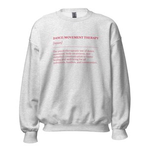 May include: A light gray sweatshirt with the text "DANCE/MOVEMENT THERAPY [noun]" in pink. The text below describes the psychotherapeutic use of dance, movement, body awareness, and communication for healing and well-being.