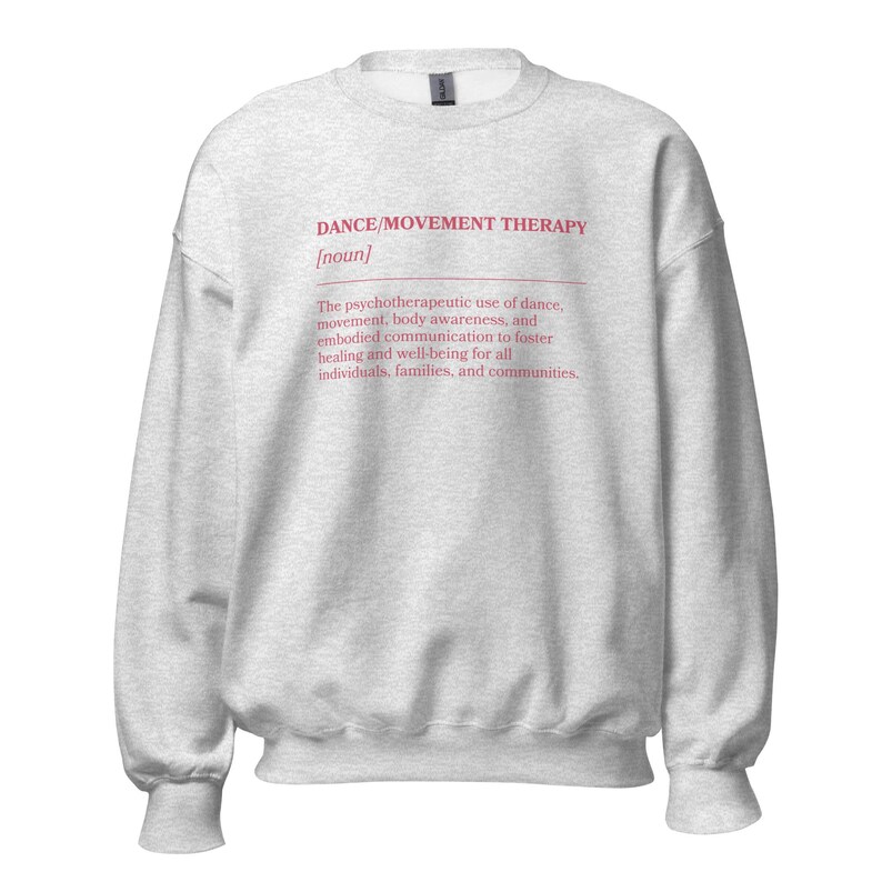 May include: A light gray sweatshirt with the text "DANCE/MOVEMENT THERAPY [noun]" in pink. The text below describes the psychotherapeutic use of dance, movement, body awareness, and communication for healing and well-being.