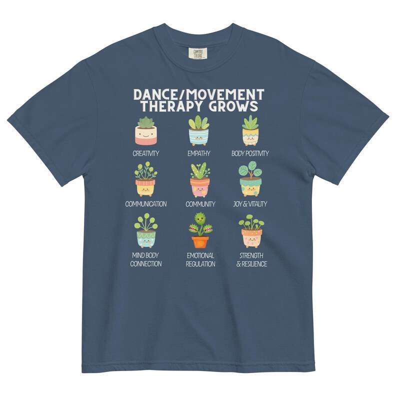 May include: A navy blue t-shirt with the text "DANCE/MOVEMENT THERAPY GROWS" and illustrations of potted plants. Each plant represents a positive concept like creativity, empathy, and joy & vitality. The shirt is made of a soft, comfortable material.