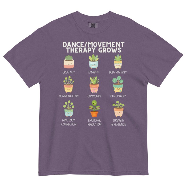 May include: A purple t-shirt with the text "DANCE/MOVEMENT THERAPY GROWS" and illustrations of potted plants representing concepts like creativity, empathy, and joy. The shirt is a comfortable, casual wear item.