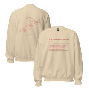 May include: A cream-colored sweatshirt with the text "DANCE/MOVEMENT THERAPY [noun]" in red. The back of the sweatshirt features a heart-shaped design with the words "DANCE AND MOVEMENT THERAPY" in a lighter shade of red.