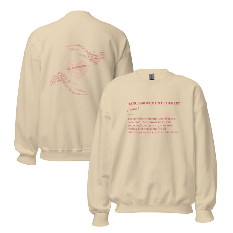 May include: A cream-colored sweatshirt with the text "DANCE/MOVEMENT THERAPY [noun]" in red. The back of the sweatshirt features a heart-shaped design with the words "DANCE AND MOVEMENT THERAPY" in a lighter shade of red.