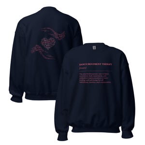 May include: Navy blue sweatshirt with the text "DANCE/MOVEMENT THERAPY [noun]" in pink. The back of the sweatshirt features a pink heart and hand design made of text. The definition of dance/movement therapy is also printed on the front.
