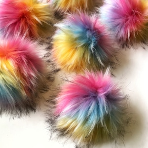 May include: A collection of colorful rainbow pom poms with black tips. The pom poms are made of fluffy faux fur and are arranged in a random pattern.