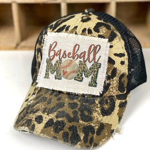 May include: A brown and black leopard print baseball cap with a black mesh back. The cap has a patch on the front that says "Baseball Mom" with a baseball and a leopard print design.