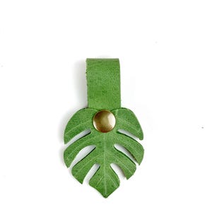 May include: A green leather monstera leaf keychain with a gold button.