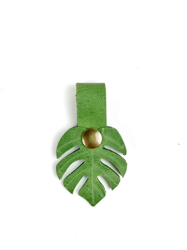 May include: A green leather monstera leaf keychain with a gold button.