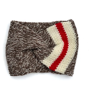 May include: A knitted headband in brown and white with a twisted knot design. The headband features a section of cream-colored stripes with a single red stripe. The accessory is designed to keep the ears warm.