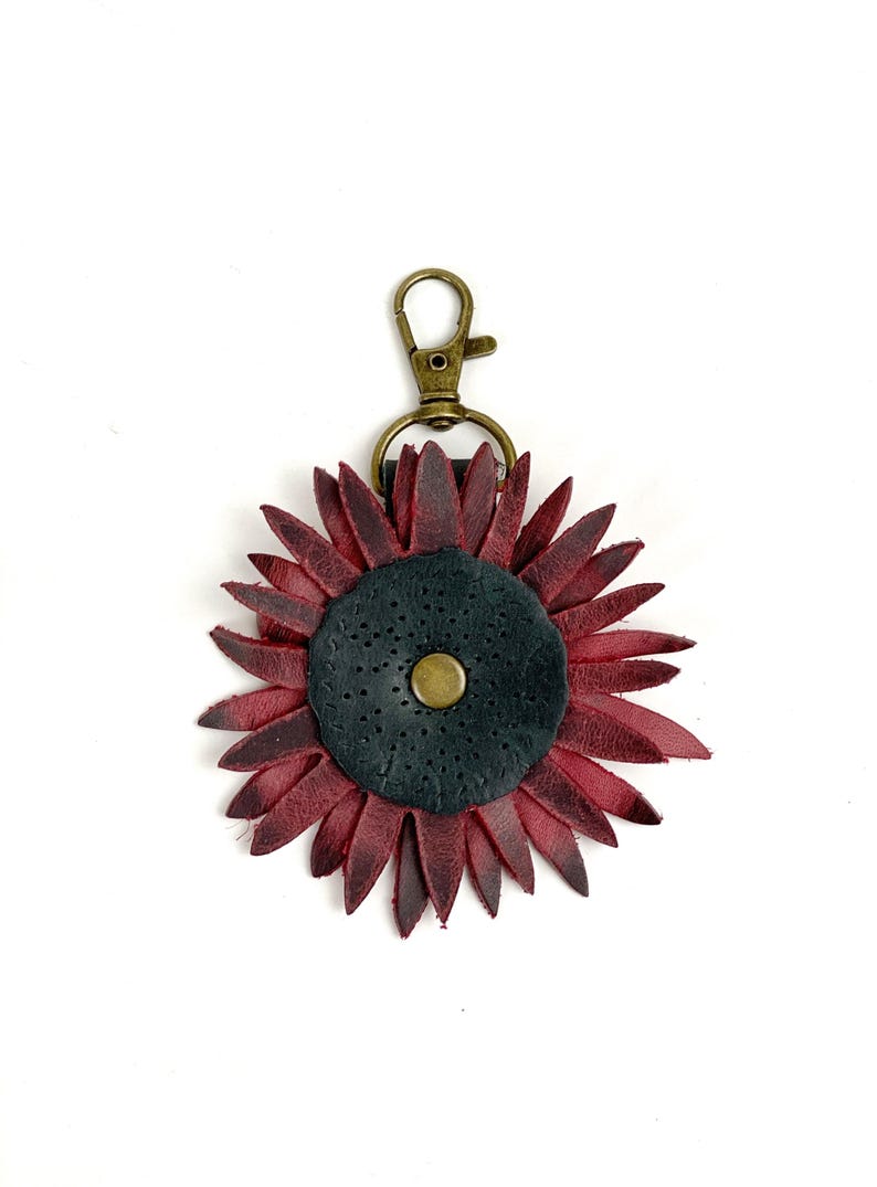 May include: A burgundy leather sunflower keychain with a black center and a gold metal clasp.