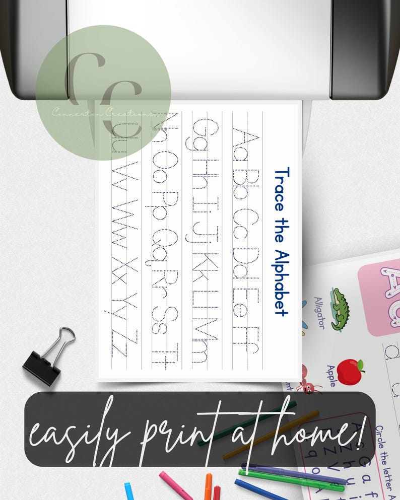 May include: A printed worksheet with the text "Trace the Alphabet" and dotted letters for tracing. The image includes the text "easily print at home!" and colourful crayons. A binder clip is also visible.