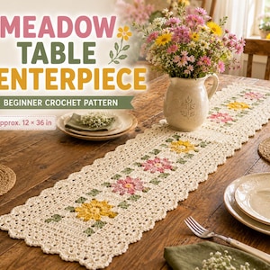 May include: A cream-colored rectangular crochet table runner featuring a floral pattern with pink and yellow flowers and green leaves. The text on the image reads MEADOW TABLE CENTERPIECE BEGINNER CROCHET PATTERN and Approx. 12 x 36 in.