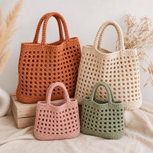 Peut inclure: Quatre sacs fourre-tout en crochet de tailles et de couleurs variées. Deux grands sacs en orange rouille et crème, et deux plus petits en rose poudré et vert sauge. Chaque sac présente un motif à grille carrée, une ouverture et deux anses.