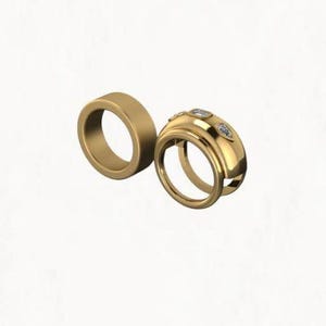 May include: Two gold rings. One is a simple band, the other is a wider band with three small, clear gemstones. The rings are displayed against a white background. The rings are likely for a wedding or engagement.