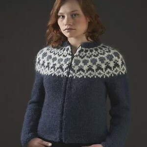 May include: A navy blue zip-up sweater with a patterned yoke in white, gray, and black. The sweater has long sleeves and is made of a textured knit fabric. The model is wearing blue jeans.