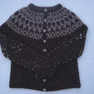 May include: A dark brown knitted cardigan with a patterned yoke in shades of gray. The sweater has a round neckline, long sleeves, and is fastened with six silver buttons. The garment is made of a thick, warm yarn.