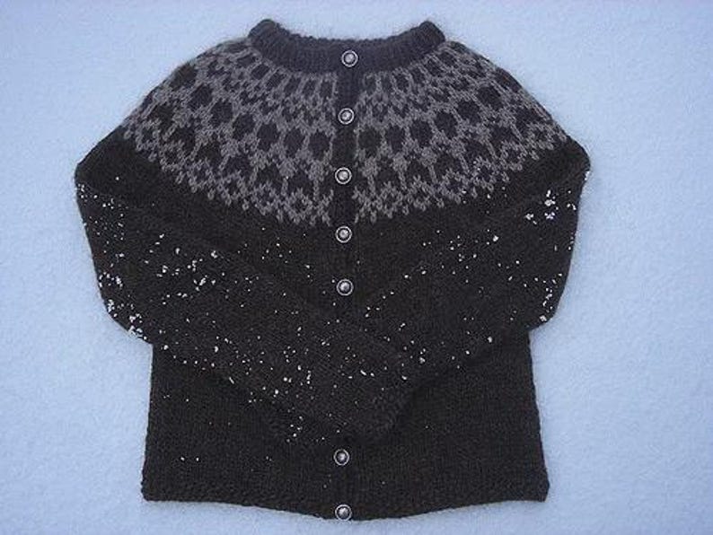 May include: A dark brown knitted cardigan with a patterned yoke in shades of gray. The sweater has a round neckline, long sleeves, and is fastened with six silver buttons. The garment is made of a thick, warm yarn.