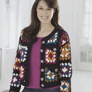 May include: A black crochet jacket with colorful square patterns in shades of white, blue, orange, and burgundy. The jacket has large, decorative buttons and a round neckline. The garment is worn over a pink top and blue jeans.