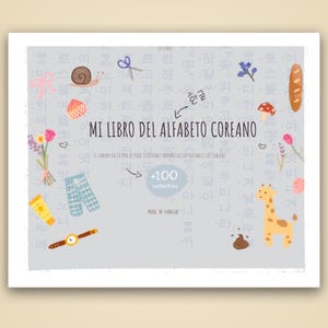 Può includere: Una copertina di libro intitolata MI LIBRO DEL ALFABETO COREANO con uno sfondo grigio chiaro e caratteri coreani. Le illustrazioni includono una lumaca, forbici, fiori, una baguette, un fungo, pantaloni, un tubetto, un orologio e una giraffa.