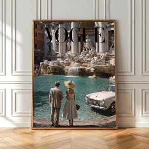 Puede incluir: Impresión enmarcada con la palabra "VOGUE" en la parte superior. La imagen muestra a una pareja con ropa vintage cerca de una fuente y un coche clásico. El escenario es un edificio histórico.