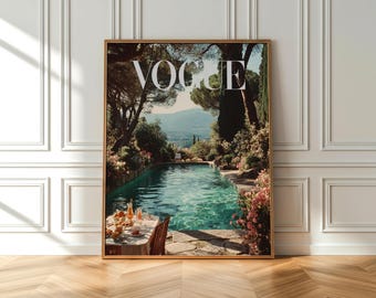 Op de afbeelding: Een ingelijste print met het woord "VOGUE" in het wit. De afbeelding toont een zwembad omringd door bomen en bloemen, met een tafel gedekt voor een maaltijd. De scène roept een gevoel van luxe en ontspanning op, met een heldere blauwe lucht op de achtergrond.