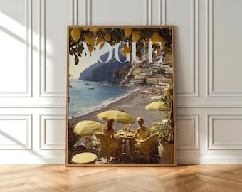 Op de afbeelding: Een ingelijste Vogue-magazinecover. De afbeelding toont een kustlandschap met het logo van het tijdschrift bovenaan. De scène omvat een strand met gele parasols, twee personen aan een tafel en een stad op een heuvel.