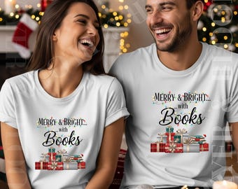 May include: Two people wearing white t-shirts with the text "MERRY & BRIGHT... with Books" printed on the front. The design includes a string of lights, gift boxes, and books. The background features a fireplace and Christmas decorations.