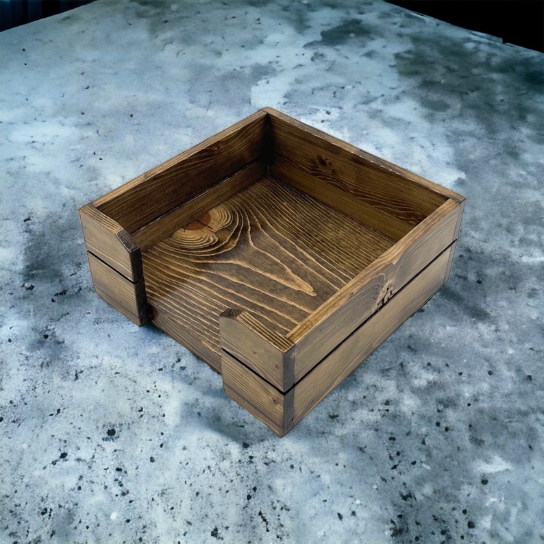 May include: A square wooden box with a dark brown stain. The box has a simple design with a smooth finish.