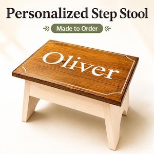 May include: A wooden step stool with a dark brown stained rectangular top and light natural wood legs. The top features the name Oliver in white lettering, enclosed within a thin white decorative border. Text above reads Personalized Step Stool Made to Order.